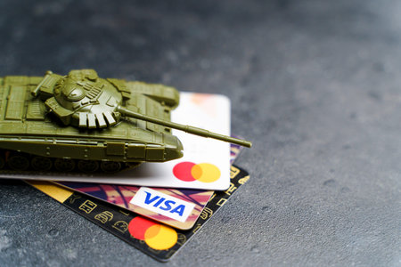Moscow, Russia - March 14, 2022: Economic crisis in Russia concept. Toy tank on plastic bank cards...