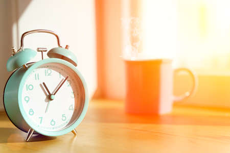 Alarm clock in the morning on the table in the bedroom against the background of the window with the morning bright sun. Wake up, time, new day, optimism conceptの写真素材