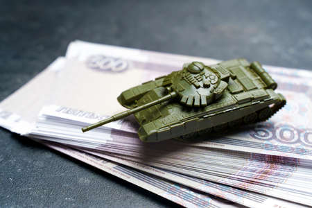 Economic crisis in Russia concept. Toy military tank on Russian rubles. War conflict in Ukraine, economic sanctions and inflation in Russiaの写真素材