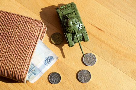 War in Ukraine and sanctions against Russia concept. Wallet with Russian rubles and a toy tank on a...