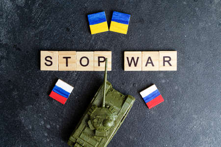 Russias war in Ukraine conflict concept. Inscription Stop war and a toy tank on a dark background. Peace, pacifism, activism and support ideaの写真素材