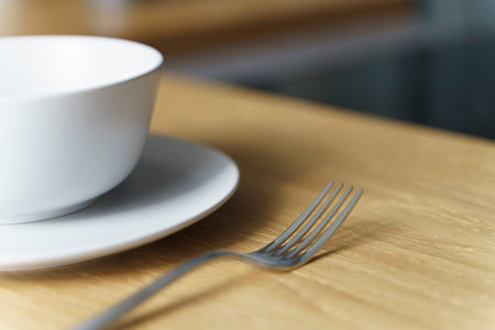 Ceramic white bowl with food and a fork on a wooden table in the kitchen in a restaurant or at home....