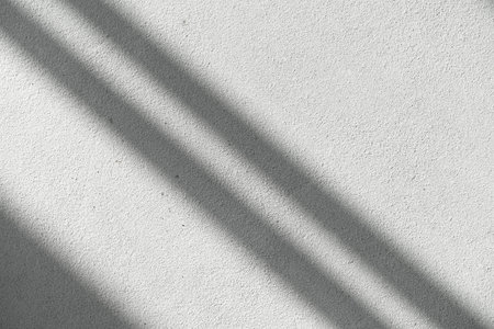 Shadows of window lines on a concrete stone wall in a bright room background. Abstract, geometry,...
