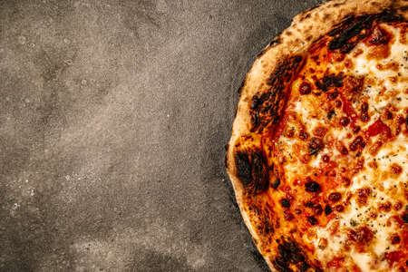 Pizza food background. Homemade Neapolitan pizza Margherita with mozzarella cheese and tomato sauce on a rustic black table. Italian food.の写真素材