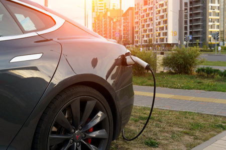 Minsk, Belarus - August 12, 2022: Tesla car charges the electric motor at the charging station on the street. Electric cars, ecology, transport concept.のeditorial素材