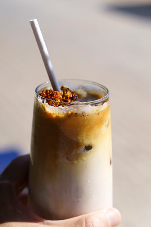 Dalgona coffee. Iced coffee drink with sugar and milk on a glass cup on a table in a cafe. Trendy cold drinks, Korean food concept.の写真素材