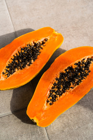 Sliced papaya on the kitchen table. Juicy ripe orange papaya ready to eat. Exotic tropical fruits,...