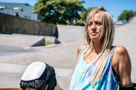 Smiling middle age woman portrait with skateboard in sport lifestyle at summer sunny day. Street urban sporty lifestyle concept.の写真素材