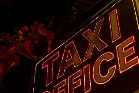 Neon red electric inscription Taxi office on the facade of the building.の写真素材