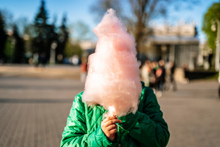 Cotton candy in the hand of a child in a summer park. Sweet food and sugar.の写真素材