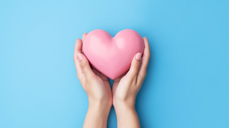 Heart in hands on a minimal background. Charity, health, care, love concept.の素材
