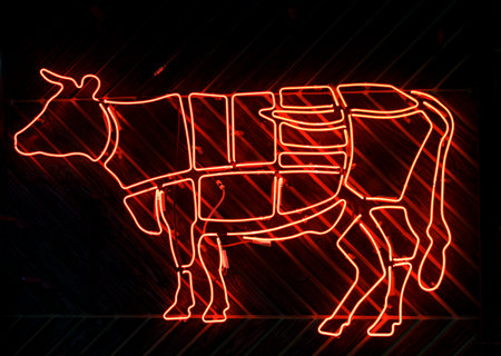 Neon sign of a cow and cutting beef into meat parts. High quality photoの写真素材