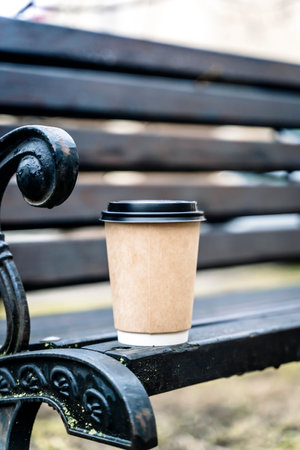 Paper cup of coffee drink to go take away on a park bench.の写真素材