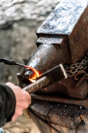Blacksmith in a forge at work on an anvil. Hot metal forging