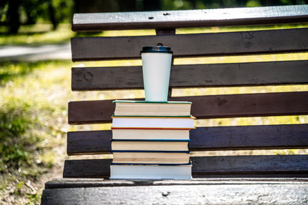 Stack of books and cup of coffee on the street in the park. Study, education, university concept.の写真素材