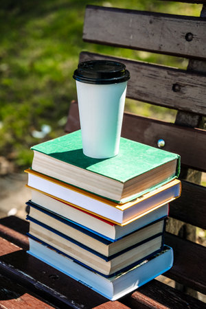 Stack of books and cup of coffee on the street in the park. Study, education, university concept.の写真素材