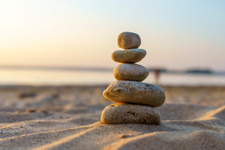 Zen stones background. Pyramid of stones on the background of sunset on the sea beach. Relax, balance, calm, concept.の写真素材