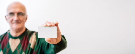 Pensioner old man holding white blank card. Finance, discounts, shopping, ID