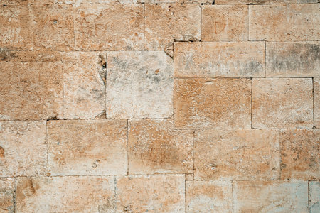 Antique ancient stone wall masonry texture background. Old wall made of beige stone blocksの写真素材