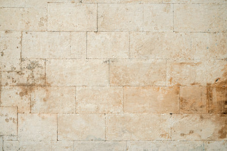 Antique ancient stone wall masonry texture background. Old wall made of beige stone blocksの写真素材