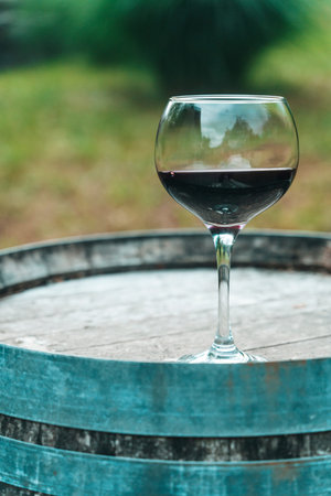 Glass of Red Wine on Old Oak Barrel in Rustic Cellarの写真素材