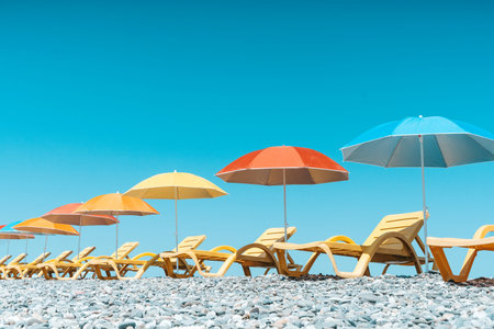 Colorful Beach Umbrellas and Sun Loungers on a Pebble Seaside