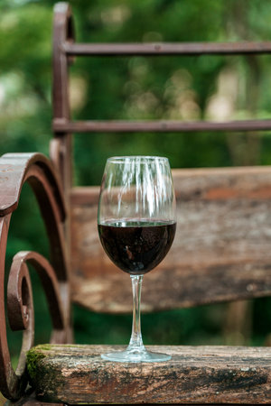 Glass of Red Wine on Wooden Bench in Summer Parkの写真素材