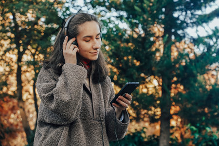 Young Woman Enjoying Music in Park During Autumnの写真素材
