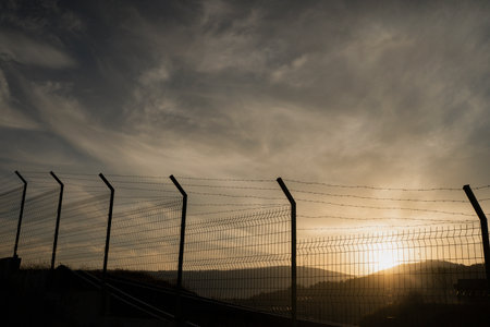 Border Fence at Sunset. Migration and Political Tension Conceptの写真素材