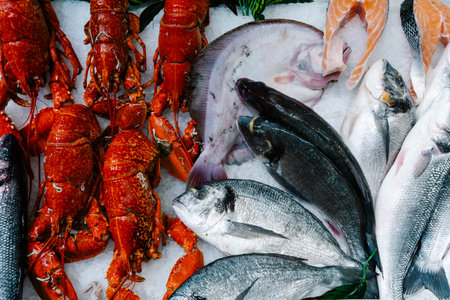 Seafood selection with red lobsters and fresh fish on ice. Top view of a luxury market display featuring gourmet crustaceans and silver sea bream at a traditional fish stall