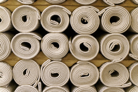 Industrial carpet production and storage with large rolls of textile flooring. Manufacturing process of various synthetic carpets in a warehouse or factory facility.