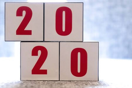 Abstract 2020 & 2019 New year countdown design concept - woman holding wood blocks cubes on wooden table and blue background, close up, copy space.の写真素材