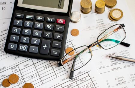 A finance still life with a jar of Sterling coins on Sterling notes, calculator and pen.の写真素材