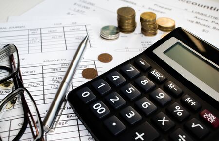 A finance still life with a jar of Sterling coins on Sterling notes, calculator and pen.の写真素材