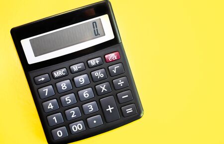 Flat lay or top view of black pen with calculator on vivid yellow background table with blank copy space, math, cost, tax or investment calculation.の写真素材