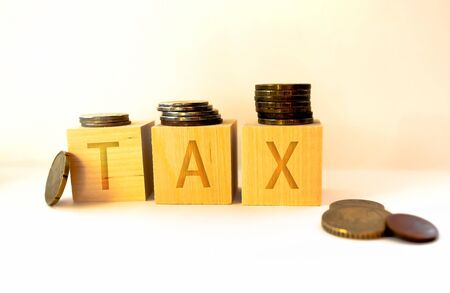 Tax Concept with wooden block on stacked coinsの写真素材