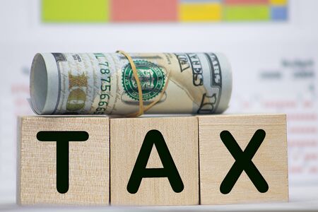 Close-up Of Person Hand Using Calculator With Tax Word On Wooden Blocksの写真素材