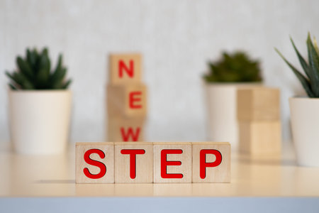 The words Next Step on small wooden dices on a table, close up shot, view from above