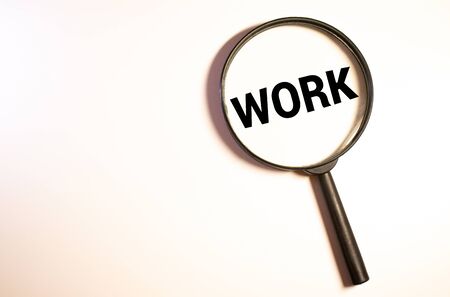 Magnifying glass over the word job wooden letters on yellow background. Top view, flat lay.の写真素材