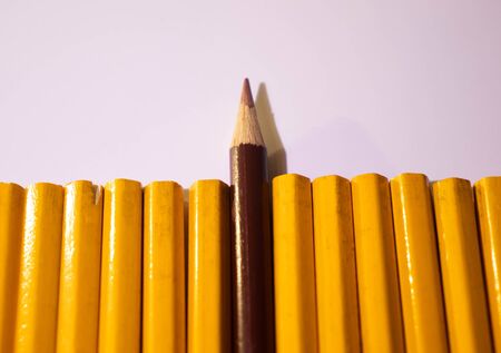 Red pencil standing out from crowd of plenty identical black fellows on white background. Leadership, uniqueness, independence, initiative, strategy, dissent, think different, business success conceptの写真素材
