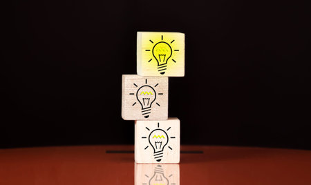 Hand picked a wooden cubes with the yellow light bulb symbol on wooden table. New idea, Innovation...