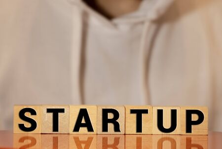 Wooden blocks with the word Startup. Temporary structure designed to find and implement a scalable business model. The concept of raising funds for a startup. Crowdfunding. Investing in the future.の写真素材