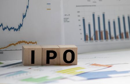A Notebook with Business notes initial coin offering ICO vs IPO Initial Public Offering with office tools on yellow blue background. Concept of the choice of IPO or ICOの写真素材