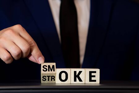 Symbol for the risk of smoking. Hand turns a dice and changes the word smoke to stroke.の写真素材