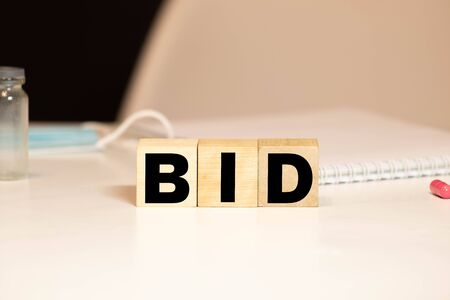 Health and medicine with the inscription BID on wooden cubes, take the medication twice a day. Medicines for the virus.の写真素材