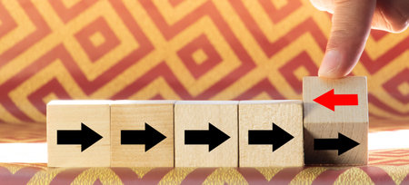 Hand flip over wooden cube block with red arrow facing the opposite direction black arrows, Unique,...