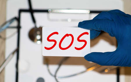 White lightbox with word SOS abbreviation of save our soul ship or sibling over shoulder on wood backgroundの写真素材