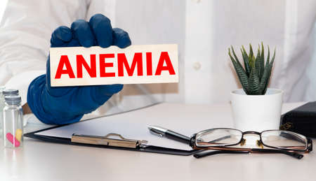 inscription anemia on a piece of paper that holds the hand of a man in a medical gloveの写真素材
