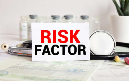 Risk factor words written on medical blue folder with patient files, pills and stethoscope on backgroundの写真素材