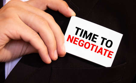 Businessman putting a card with text TIME TO NEGOTIATE in the pocketの写真素材